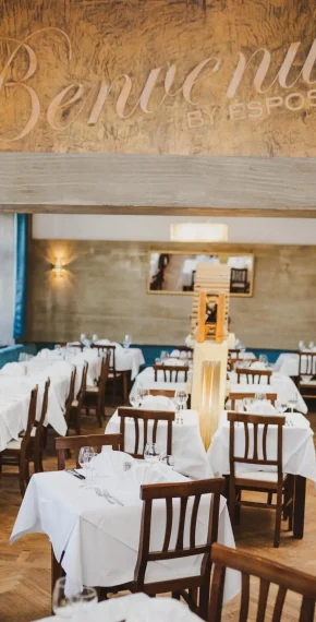 Eleganter Gastraum des Ristorante Pizzeria Ciao in der Balanstraße in München nahe Ostbahnhof mit weiß gedeckten Tischen und Benvenuti-Schriftzug.